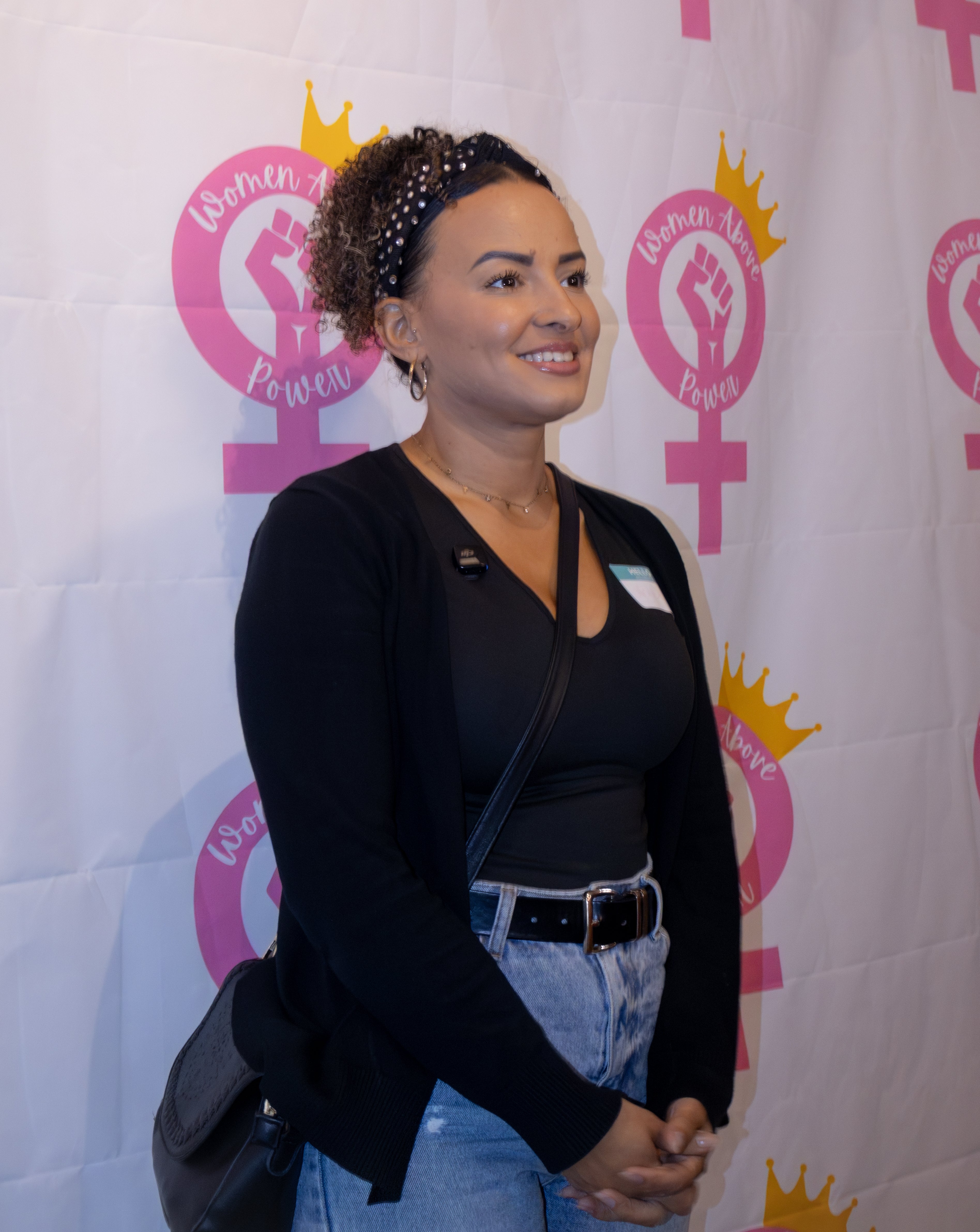 Woman standing in front of a backdrop with 'Women of Power' logos.

